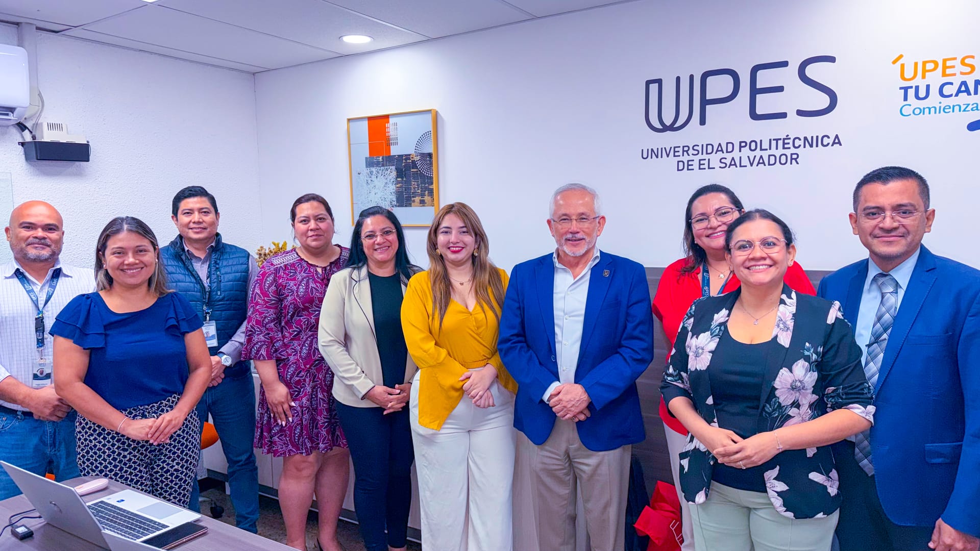 Equipo de colaboradores de la UPES posando frente al logo institucional