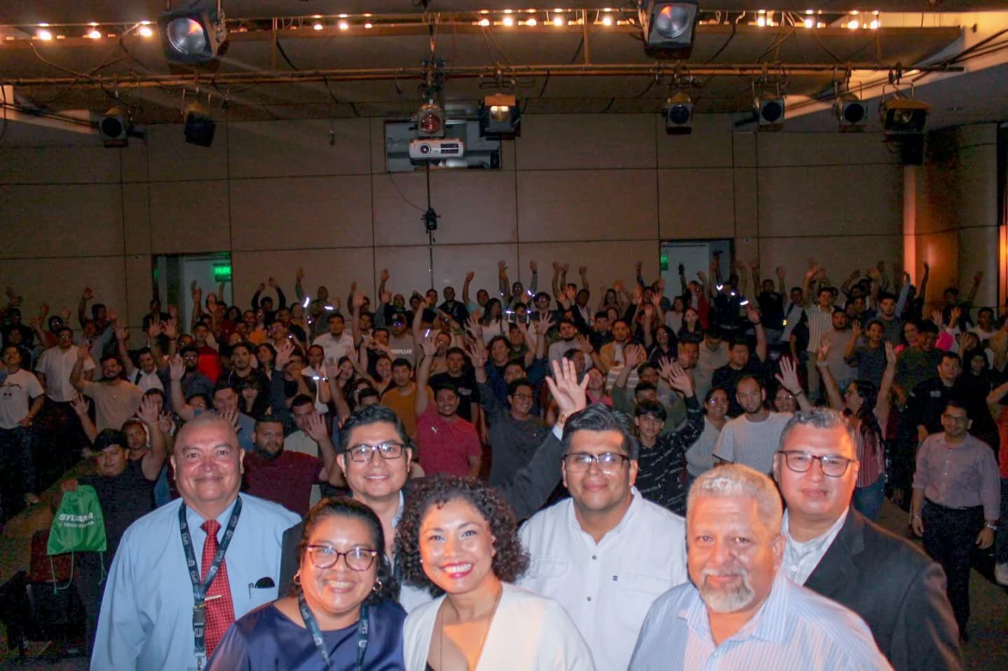 Colaboradores de la UPES con las manos en alto durante un evento